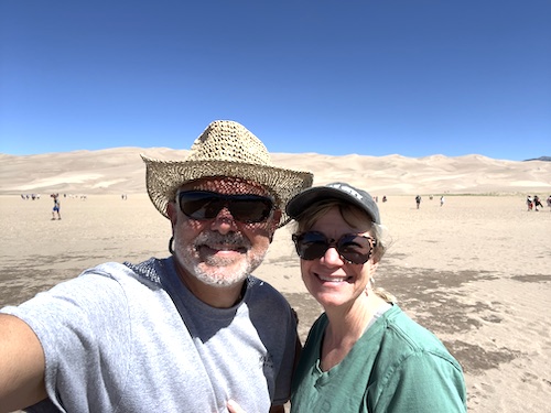 Mike and Susan from RVBlogger in front of the sand dunes at Great Sand Dunes National Park in Colorado
