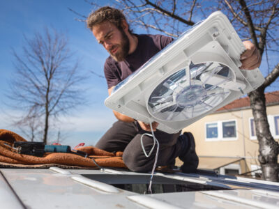man installing a rooftop fan into a van