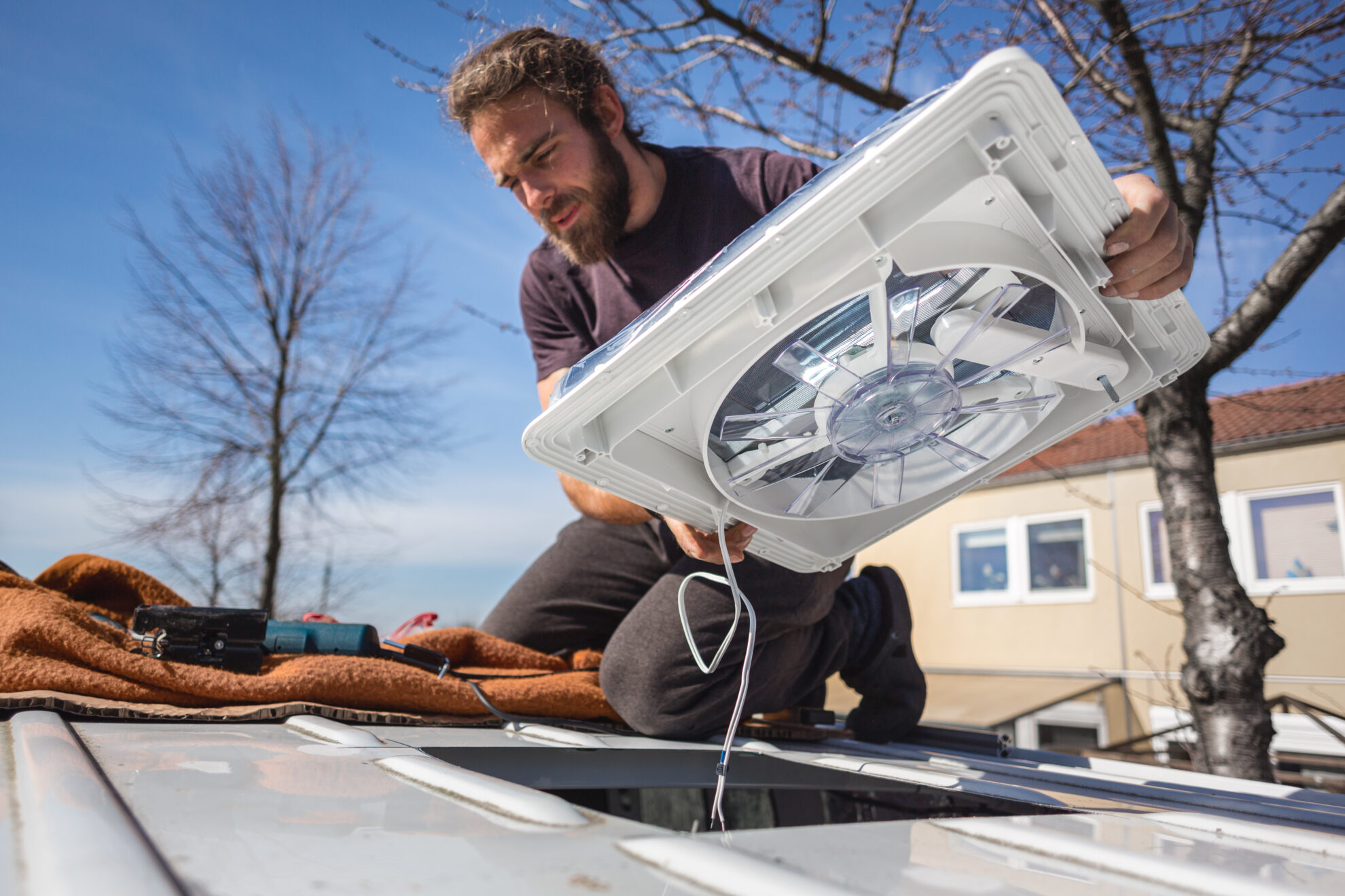 man installing a rooftop fan into a van