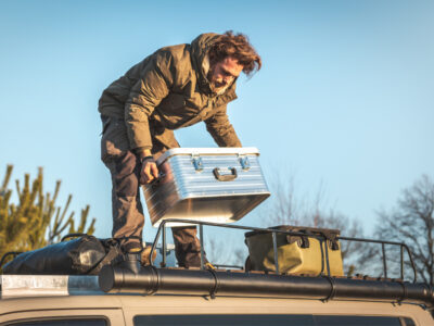 man loading a van roof rack with gear
