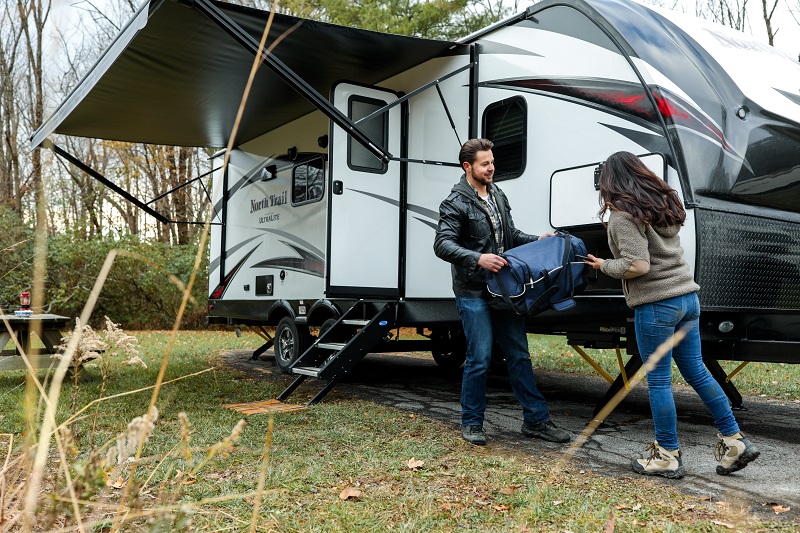 Man and woman unpacking an RV at a campsite - level RVs with slides in or out