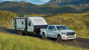 White truck towing a travel trailer in grass covered hills