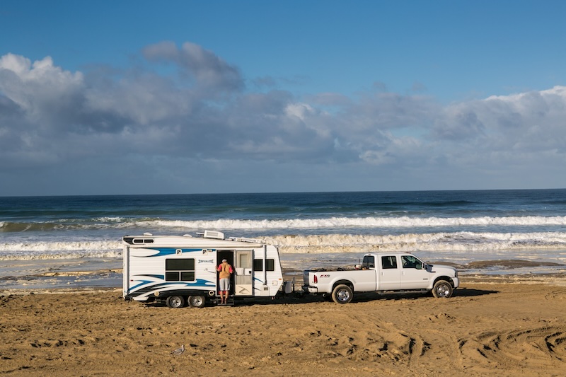 Large truck towing a travel trailer on the beach
