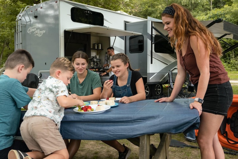Family at a table outside a travel trailer
