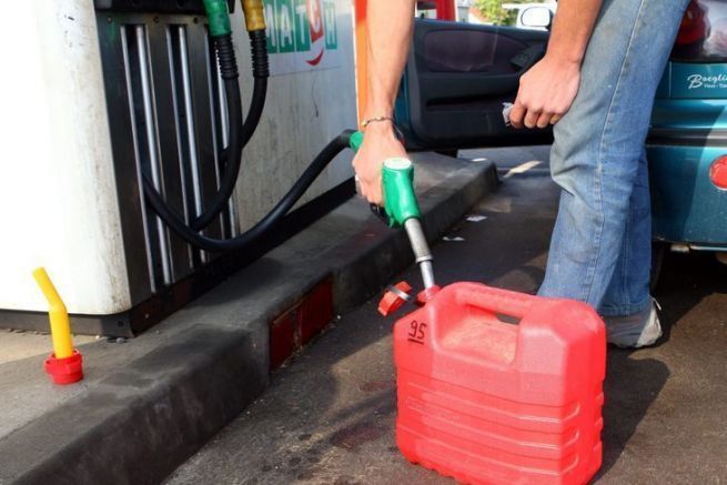 Person filling a jerry can at a gas station