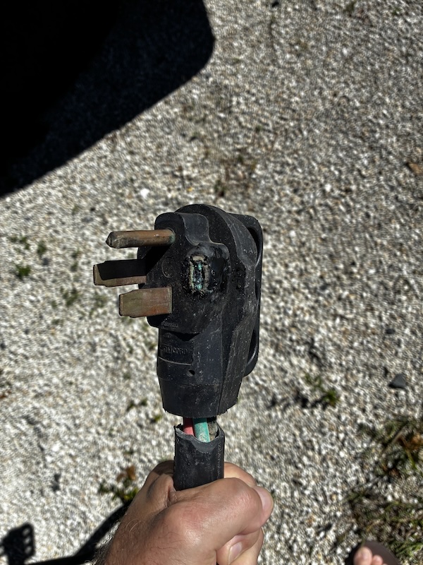 mike holding a melted 50 amp rv cord with one of the prongs broken off