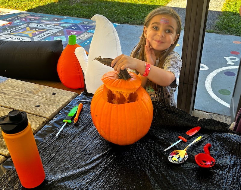 my grand daughter carving a pumpkin